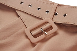 Detailed macro view of the dusty pink trouser waist featuring a fabric-covered buckle