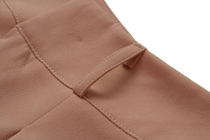 Close-up of khaki woven trousers showing waistband detail and precise stitching