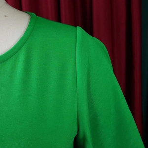 Detailed view of the bright green round neck top featuring textured knit fabric and neat seams