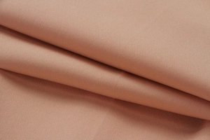 Close-up of nude pink fabric texture showing fine plain weave and soft drape