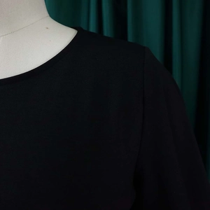 Detail of black knit dress neckline featuring professional round neck and refined stitching
