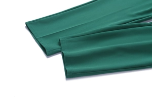 Detail of emerald green dress pants showing high-quality stitching and fabric hem