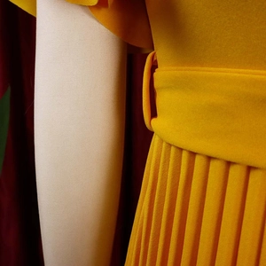 Detailed view of ginger yellow pleated dress with waist belt loops and accordion folds