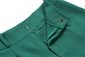 Detailed view of the metal hook closure and zipper on these green high-waist trousers