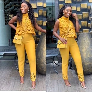 Detail of bright yellow two-piece set featuring floral lace cutout top and slim trousers