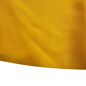 Close-up of mustard yellow pleated fabric texture with fine granular knitting detail