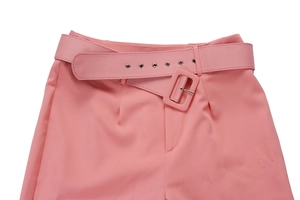 Detail of high waist pink suit trousers featuring a matching fabric belt with silver eyelets