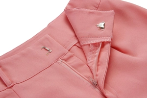 Detail of pink trousers showing waist closure with a zipper and metal hook fastener