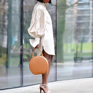 Puff sleeve shirt dress paired with a round tan leather handbag in a street setting