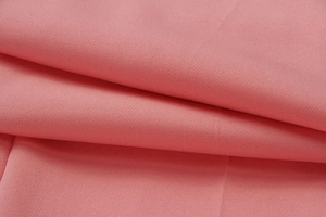 Macro shot of soft pink high-waist trousers fabric showing texture and drape detail
