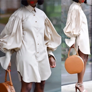 Detailed view of oversized puff sleeves and curved hem on the cream shirt dress