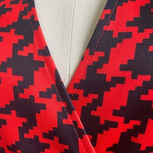 Detail of V-neck cross design on red and black houndstooth pattern jumpsuit fabric