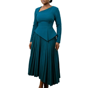 Detail of teal long sleeve dress featuring asymmetric pleated hem and cutout neckline