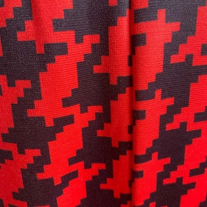 Detailed macro view of high-quality red and black geometric knit fabric with pixelated pattern