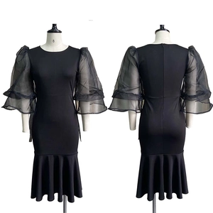 Detail of elegant mesh puff sleeves and ruffled mermaid hemline on black dress
