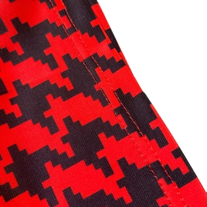 Macro detail of high-waisted wide-leg jumpsuit fabric with red black pixel print
