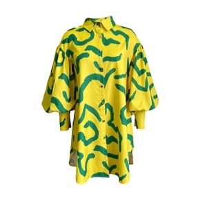 Detail of a bright yellow shirt dress featuring green abstract prints and oversized puff sleeves