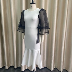 Detail of white fishtail dress featuring black sheer mesh puff sleeves and ruffled cuffs