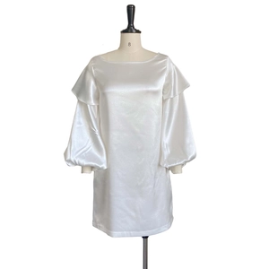 Detail of elegant white satin dress featuring ruffled off-shoulder neckline and lantern sleeves