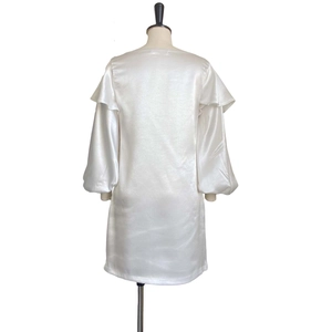Detail of white satin dress featuring ruffled shoulders and elegant puff lantern sleeves