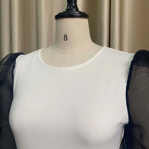 Detail of elegant two-tone dress featuring sheer black mesh puff sleeves and white bodice