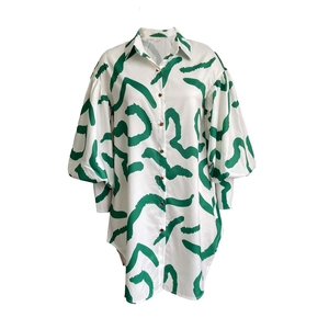 Detail of the puff sleeve design and abstract green print on this white midi shirt dress