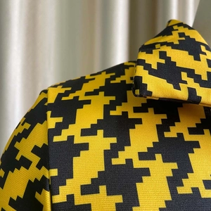 Detailed macro view of yellow and black pixelated houndstooth fabric pattern on garment