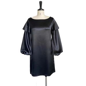 Detail of black satin dress featuring off-shoulder ruffles and elegant lantern sleeves