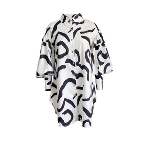 Detail of white shirt dress featuring black abstract patterns and elegant lantern sleeves
