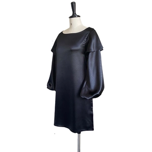 Detail of elegant black satin dress featuring voluminous puff sleeves and ruffled shoulders