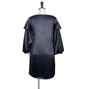 Detail of black satin mini dress featuring off-shoulder ruffles and lantern sleeves
