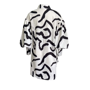 Detailed view of long sleeve shirt dress with abstract black wave prints on white fabric