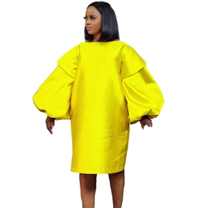Detail of loose-fit yellow shift dress featuring voluminous puff sleeves and round neck