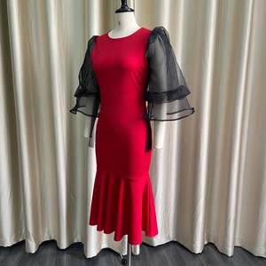 Detail of red fishtail dress with sheer black mesh tiered lantern sleeves and crew neck
