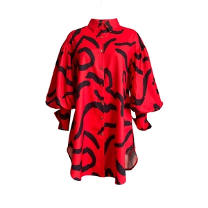 Detail of red lantern sleeve shirt featuring black abstract print and gold buttons