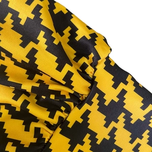 Close-up of yellow and black houndstooth pattern fabric on high-waist wide-leg jumpsuit