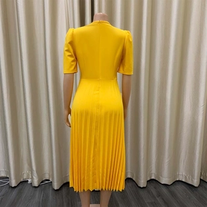 Detailweergave van de gele zomerjurk met plooien en een verborgen ritssluiting achter
