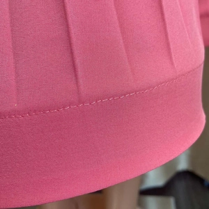 Détail du tissu plissé rose foncé montrant la texture tissée fine et les coutures précises