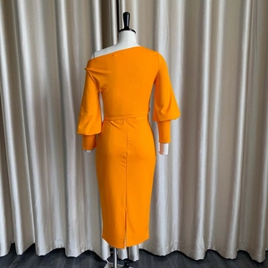 Detalle del vestido midi naranja vibrante de un hombro con mangas farol y una abertura