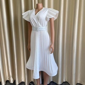 Détail de la robe plissée blanche avec col en V, manches volantées et ceinture