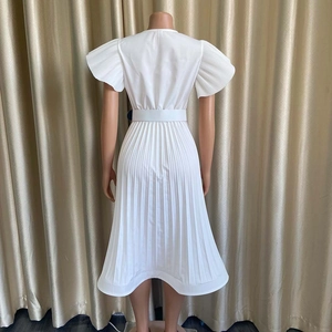 Détail d'une robe midi plissée blanche avec manches en éventail et ceinture assortie