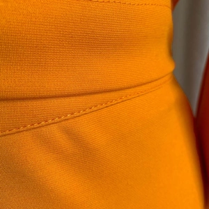 Primer plano de tejido de punto naranja con costuras planas de alta calidad y textura