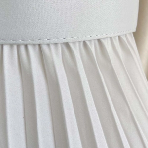 Gros plan sur le tissu plissé blanc montrant les coutures fines et la texture plissée