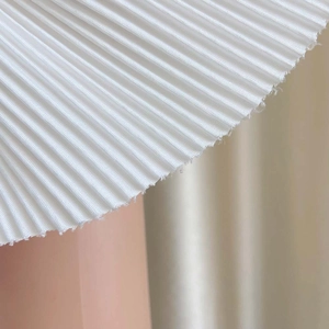 Détail du tissu blanc plissé avec des plis verticaux élégants et une texture tissée fine
