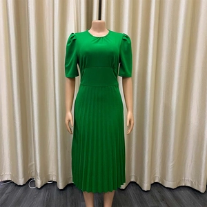 Detail van groene geplooide jurk met gepofte mouwen en hoge taille op een paspop