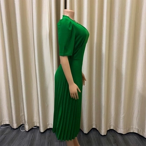 Detail van een felgroene geplooide midi-jurk met halflange mouwen en een hoge taille