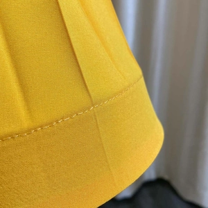Détail du tissu plissé jaune vif montrant les coutures fines et la texture de la robe