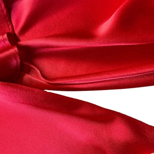 Macro detail of red satin fabric showing smooth texture and elegant glossy folds