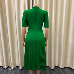 Detail van de smaragdgroene geplooide midi-jurk met pofmouwen en rits aan de achterkant