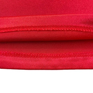 Close-up of bright red satin fabric showing high-quality double-stitch hem details